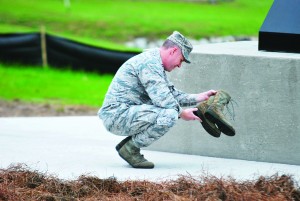 Local Air Force Chaplain Doug Lumpkin looks over a pair of boots meticulously placed at the foot of the Blackhawk Memorial in Navarre Park. Those boots were worn by first responders as they scoured the shorelines of the sound following the crash last year recovering missing bodies and helicopter parts.  (Photo by Mat Pellegrino | South Santa Rosa News)