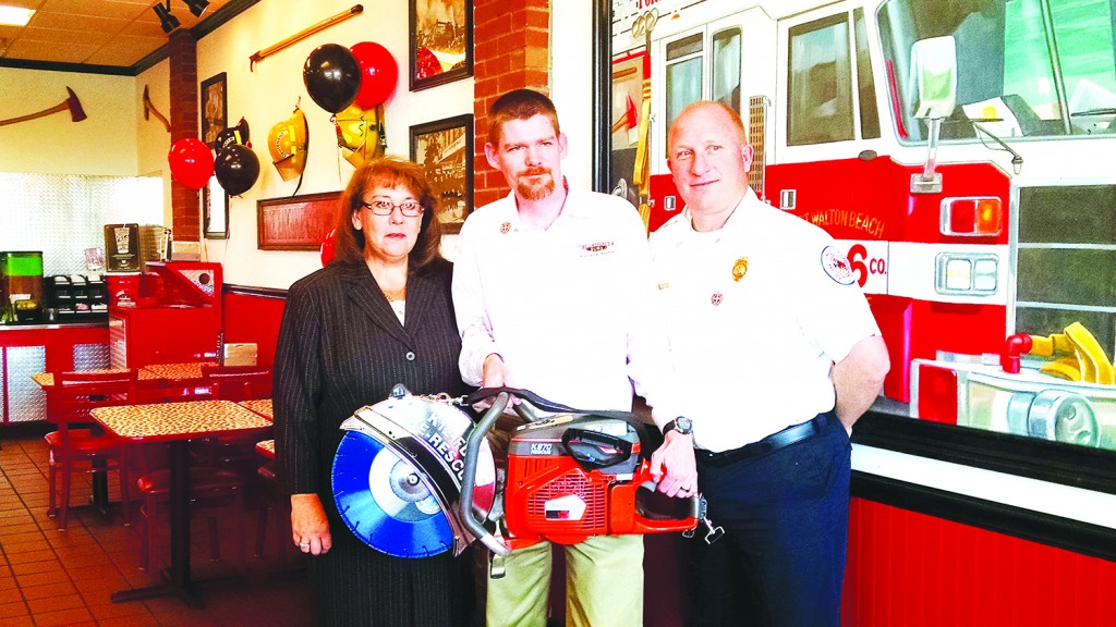 From left, Melissa Severt, District Administration Manager; Firehouse Subs Franchisee Chris Broscious (Navarre Firehouse Subs); and Battalion Chief Howard Rounsaville show off one of their purchases in Ft. Walton on Wednesday.  (Submitted Photo)