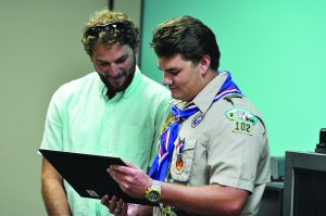 Gulf Breeze High School graduate Hunter Musil looks over his Eagle Scout award with brother, Adam, last Saturday. (Photo by Mat Pellegrino | South Santa Rosa News)