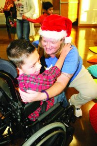 Alisha Justice, a special education Pre-K teacher at West Navarre Intermediate School and Starfish Project board member, gets a hug from Kaden Cortello at Tuesday’s Christmas celebration at the Tiger Point Community Center.  (Photo by Romi White | SSRN)